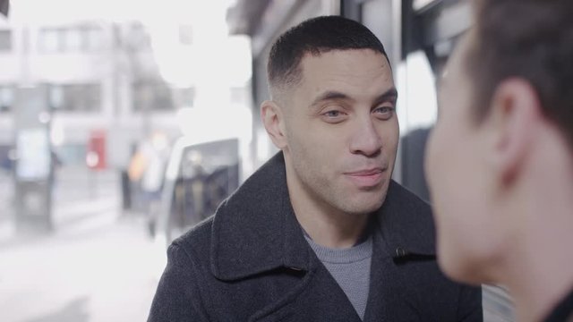 Attractive mixed race male talking before kissing her partner outside a coffee bar