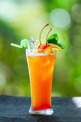 Orange cocktail with ice in glass on the background of nature. Cocktail on the background of the bar. Orange alcoholic cocktail in a traditional glass. Place to write a recipe