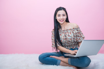Young Asian woman working on her laptop while relaxing