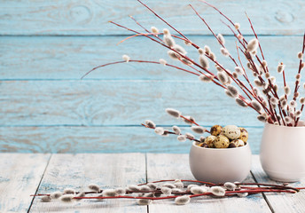 Willow branches and quail eggs on a wooden background