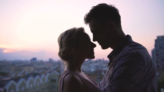 Young lovers tenderly enjoying each other against backdrop of beautiful sunset