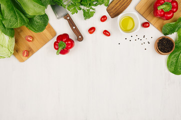 Healthy eating concept - fresh green salad, cherry tomatoes, paprika, spinach and olive oil on white wood board, top view.