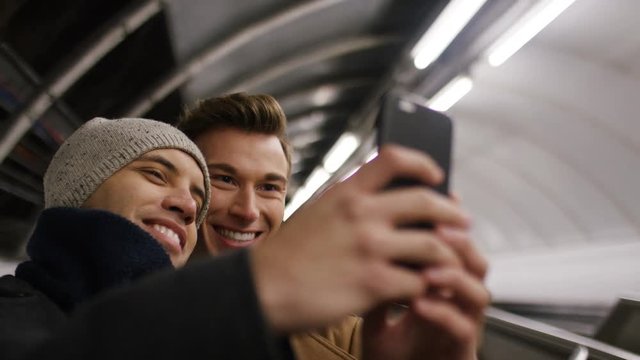 Happy young male couple take a selfie on a subway escalator 
