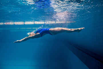 underwater picture of young female swimmer exercising in swimming pool