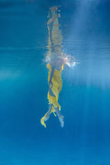 partial view of woman in dress swimming underwater
