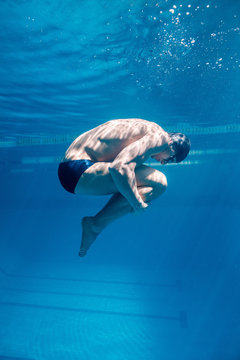 underwater picture of male swimmer in cap and goggles