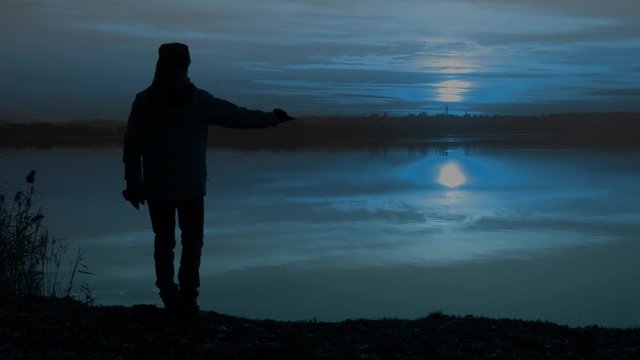 Un uomo osserva la luna sul mare