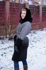 Happy and smiling woman on weekend. Lady in a striped coat walks on the street enjoying fresh air away from the city and bustle. Concept of pleasure from every day and life 