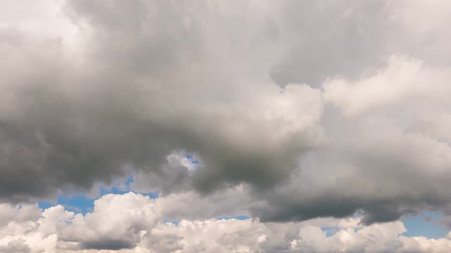 Time lapse of the sky with moving white and gray cumulus clouds.