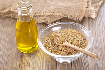 Bottle of flax seed oil ans seeds on wooden table.