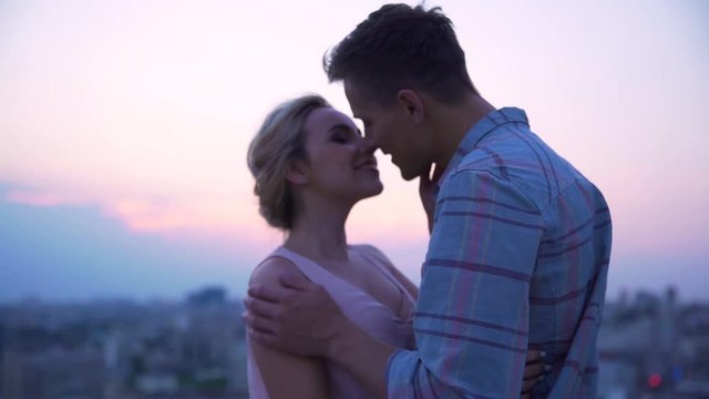 Couple in love dancing slowly on roof of house, enjoying freedom and kissing