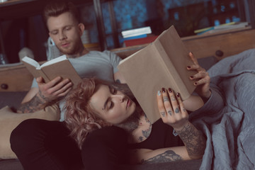 tattooed couple relaxing and reading books at home