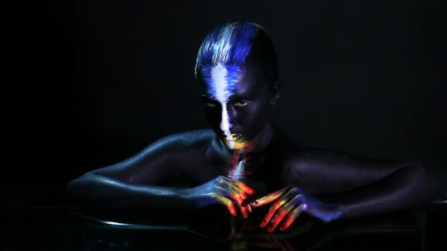 Body art portrait of a dark-skinned glowing girl with color make-up
