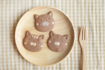 Fototapeta na wymiar Three Pieces of Homemade Chocolate Cookies Cat Face in Wooden Plate and Folk 