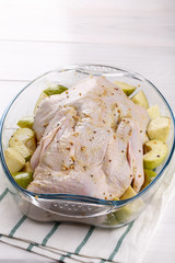 Raw duck with apples in glass roasting pan, ready for baking.