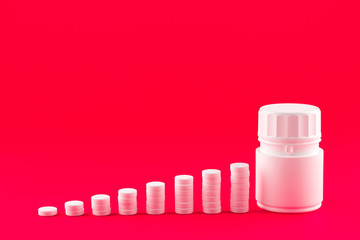 Close up pyramid concept of white pills and bottle on candy apple background with copy space. Focus on foreground, soft bokeh. Pharmacy drugstore concept