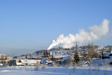 Winter view of the Urals village with a working obsolete metallurgical plant in the middle of it..