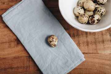 Quail egg isolated on blue napkin near ceramic bowl