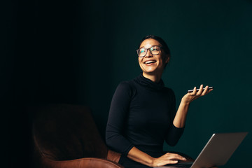 Young woman with laptop talking on phone