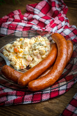Thin sausages with vegetable salad on plate.