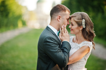 Lovely wedding couple walking along the green alley which leads to a church.