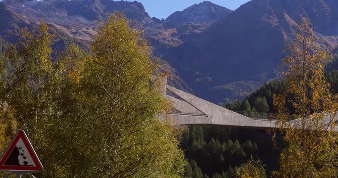 Large bridge, Cinema 4k pan view of a ganterbrucke bridge between fall color alpine forest, on the bottom of simplon pass, on a sunny autumn day, in Valais, Switzerland