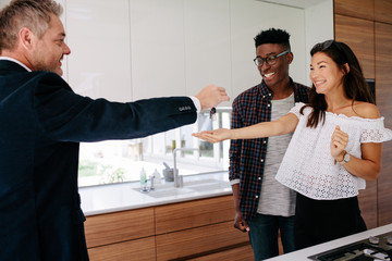 Estate agent handing over keys of new home to female buyer