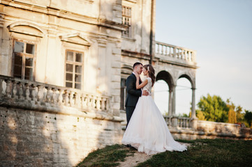 Obraz premium Fabulous wedding couple posing in front of an old medieval castle in the countryside on a sunny day.