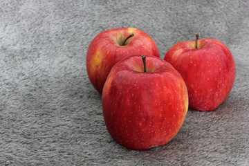 Red apples on wool. Apples on a gray background. Fruit