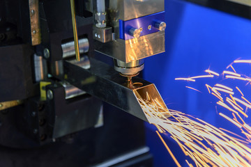 The laser cutting machine cutting the stainless square tube control by CNC program.The sparking light from laser cutting machine.