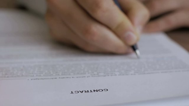  The man corrects and fills the document. Businessman signing business contract agreement, close up of male hand with pen writing signature.