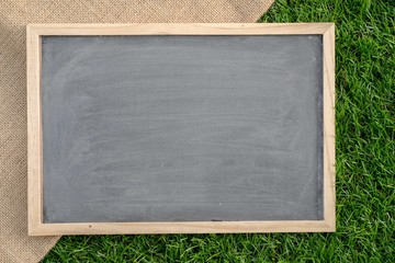Abstract chalk blackboard with wood border frame on grass floor included copyspace ready used as background for add text or graphic