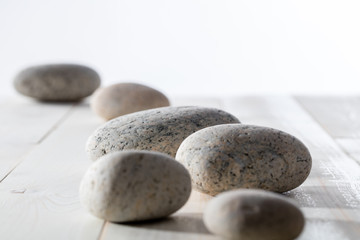 Fototapeta na wymiar pebbles set on white wooden background for mindfulness or yoga