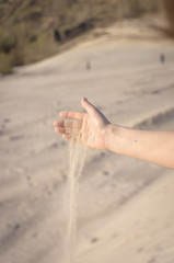 A female hand with sand. Woman pouring sand