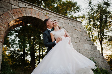 Bride and groom smiling and having great time in the forest next to the old brick bridge.