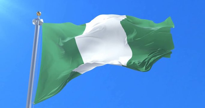 Flag of Nigeria waving at wind in slow in blue sky, loop