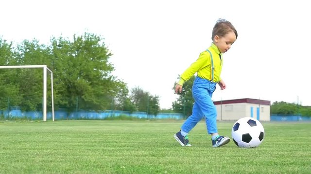 A child on a football field plays with a soccer ball, in a slow motion