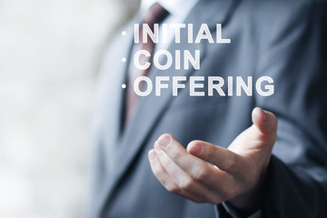 Businessman presses button ICO Initial Coin Offering on virtual digital electronic user interface.