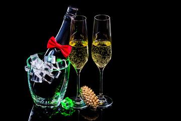 Bottle of champagne in ice bucket and two wineglasses and fir cone