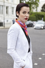 Woman standing in street wearing short white linen jacket