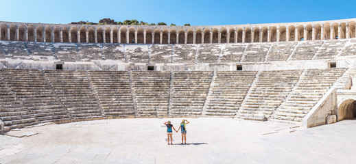 Two young girls student traveler enjoy a tour of the ancient Greek amphitheater