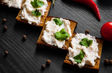 Slices of bread with cream cheese on a dark wooden background
