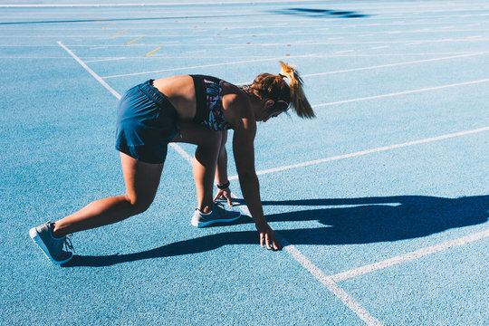 Fit woman oractising for marathon on blue running track