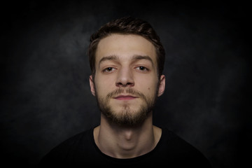 Fototapeta premium Portrait of a young man with a beard on a dark background.