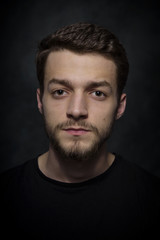 Obraz premium Portrait of a young man with a beard on a dark background.