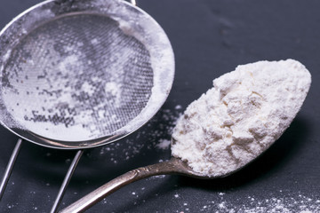 white wheat flour in an iron spoon