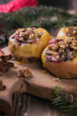 Baked apples stuffed with berries, walnuts and honey on a wooden cutting board.