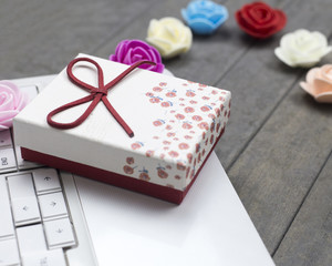 close up roses, white laptop and red gift box on background