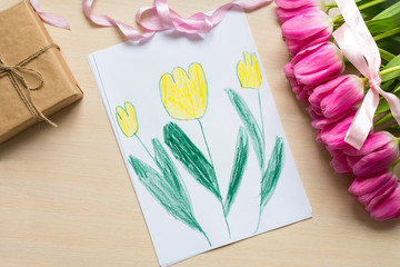 Little boy paints greeting card for Mom on Mother's Day or 8 March. Top view
