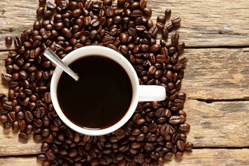 Top view, A coffee cup with roasted coffee beans on the old wood background
